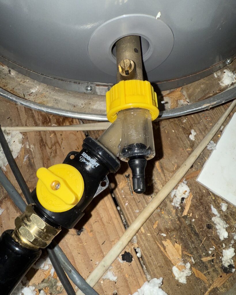 Sediment Buster tool and flush hose connected to an attic water heater drain valve in Stone Oak